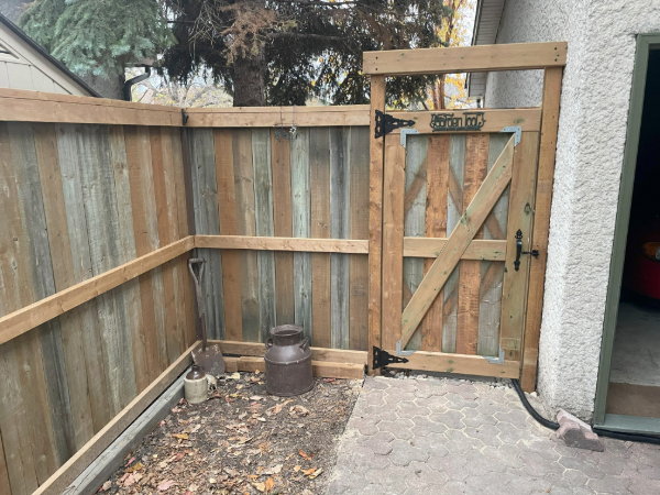  a fence connected to a garage with a wooden door
